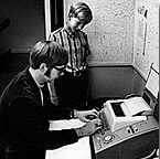 Paul Allen digitando en una computadora de la poca, mientras el jven Bill Gates lo observa